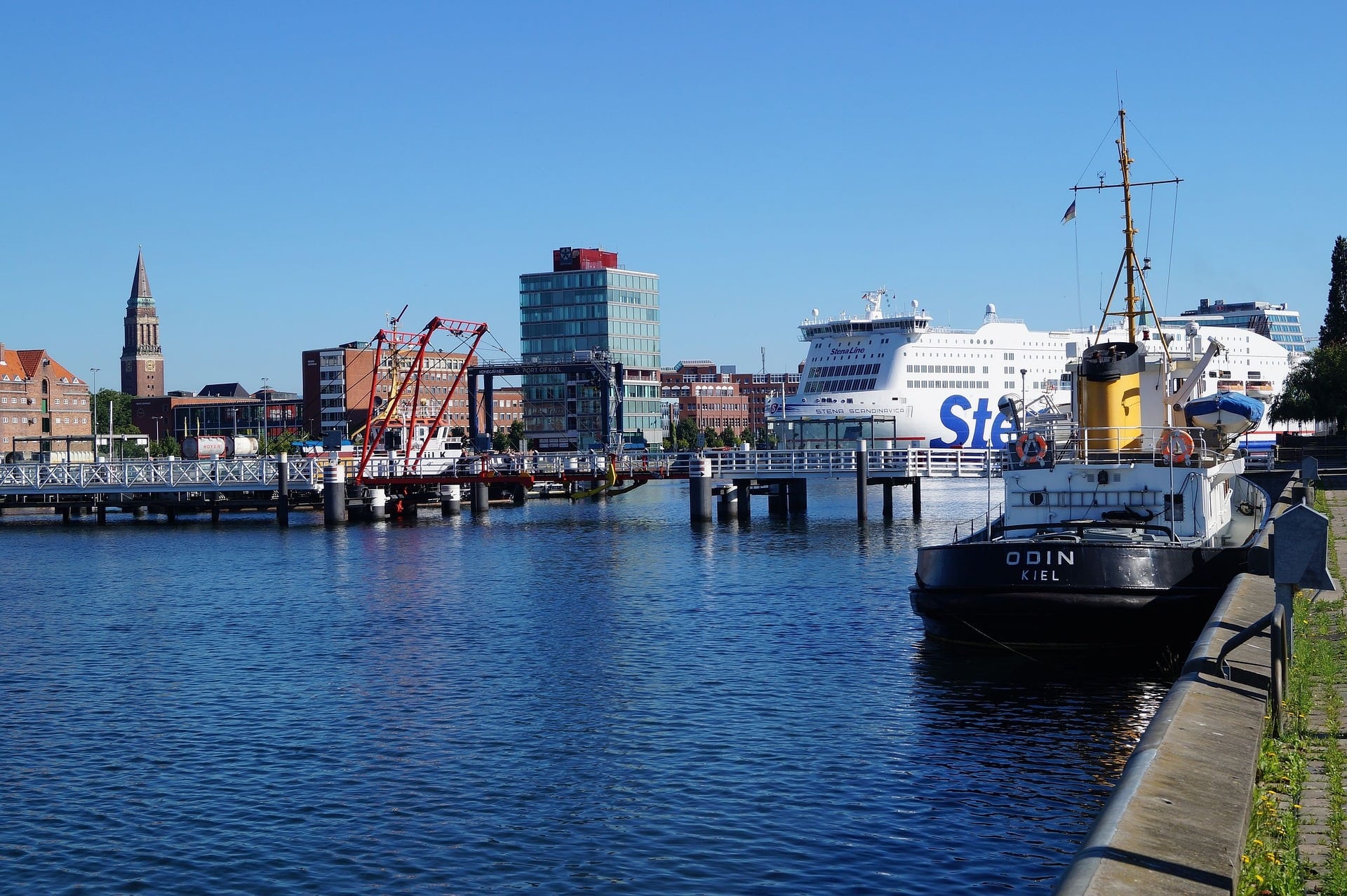 Hafen mit Segelbooten und Gebäuden an der Kieler Förde bei klarem Himmel